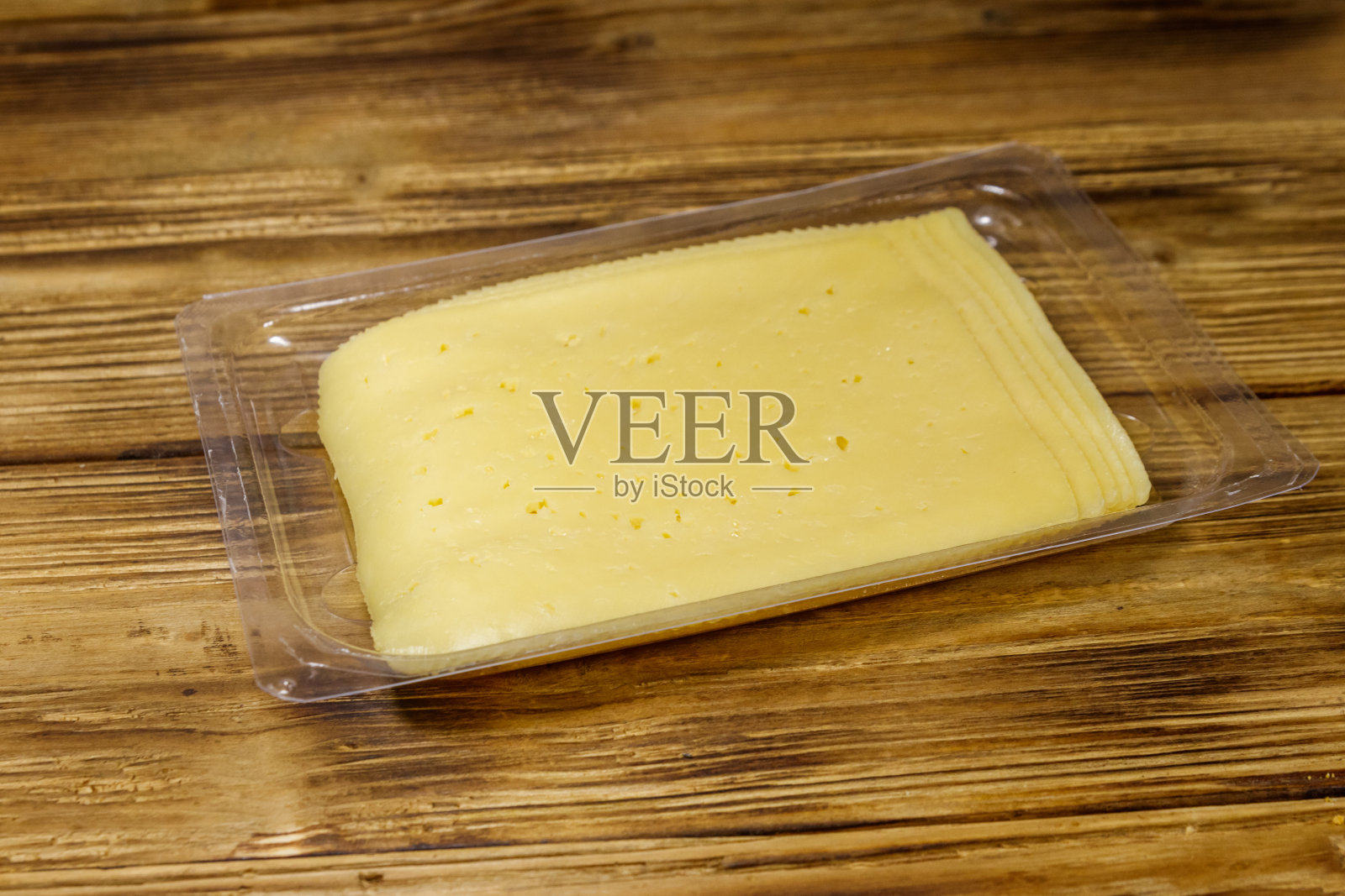 一次性塑料包装盒中的奶酪片放在木桌上照片摄影图片