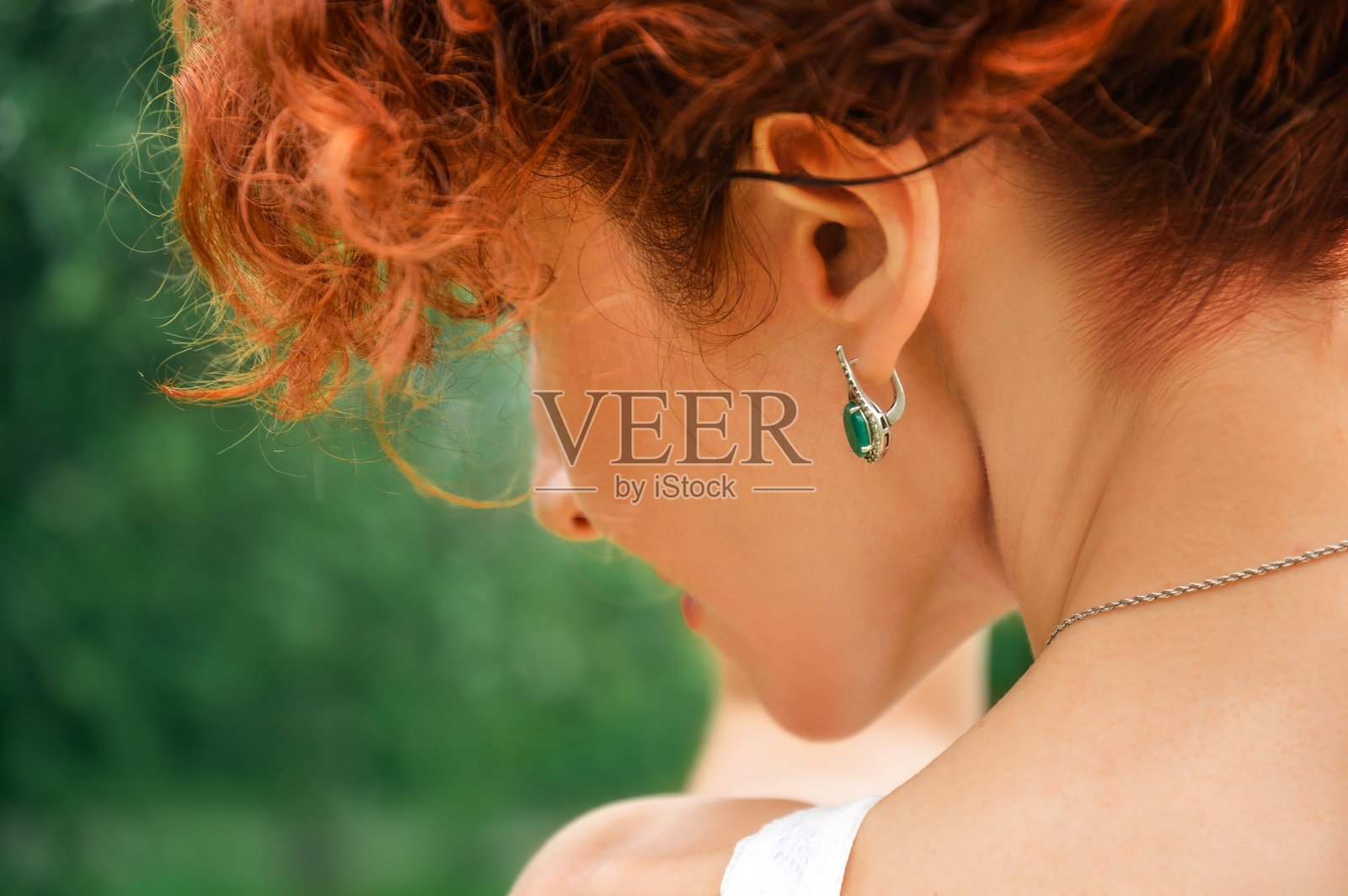 近,宏。一个红发女孩的肖像从背后看,你可以看到优雅的脖子和耳朵与银饰的祖母绿。照片摄影图片