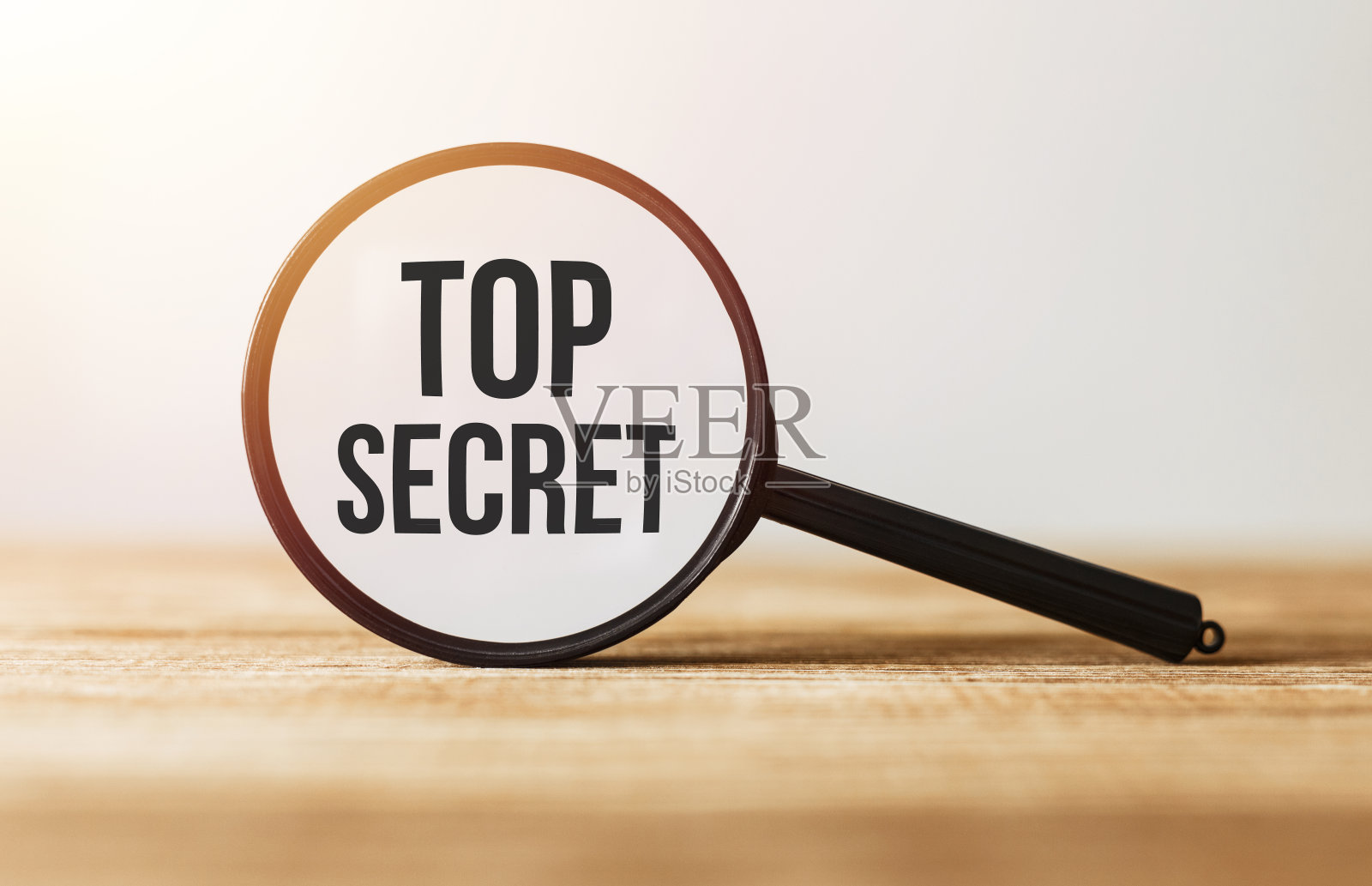 木桌上放着“绝密”字样的放大镜。照片摄影图片