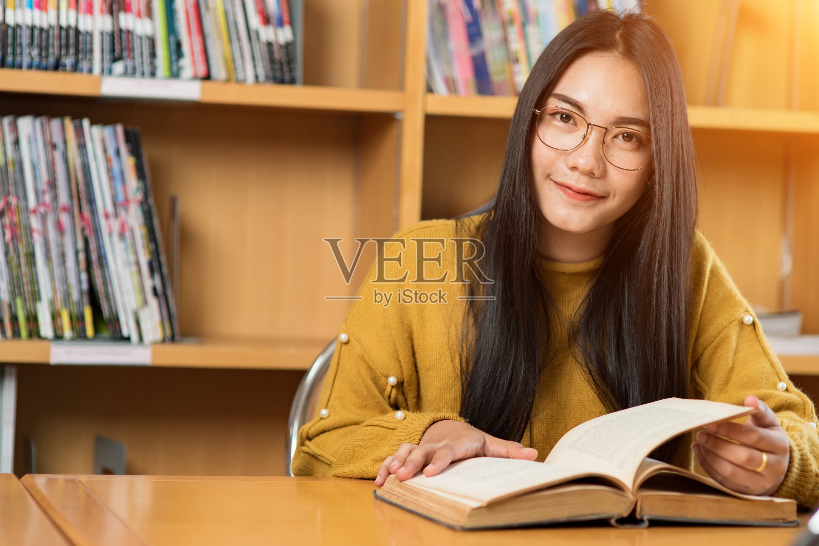 年轻的女学生在大学图书馆里研究和读书。照片摄影图片