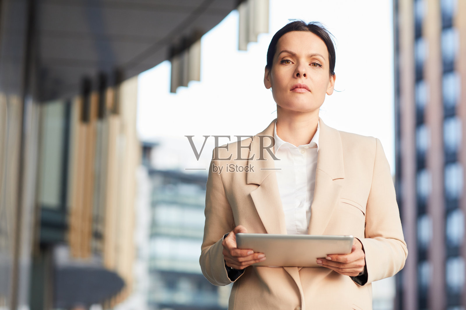 端庄自信的中年女企业家的肖像,穿着时尚的夹克,站在商业区和使用平板电脑照片摄影图片