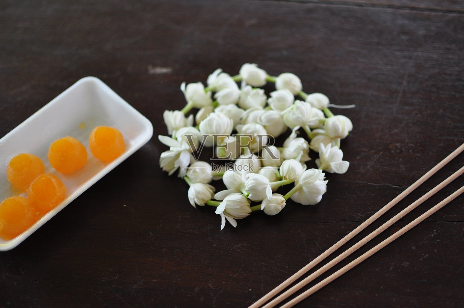在泰国,香香的茉莉花花环被围在木桌上,传统上用于祭祀鬼魂和神灵。照片摄影图片
