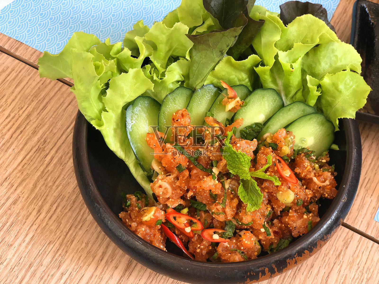 木桌上的三文鱼辣味沙拉照片摄影图片