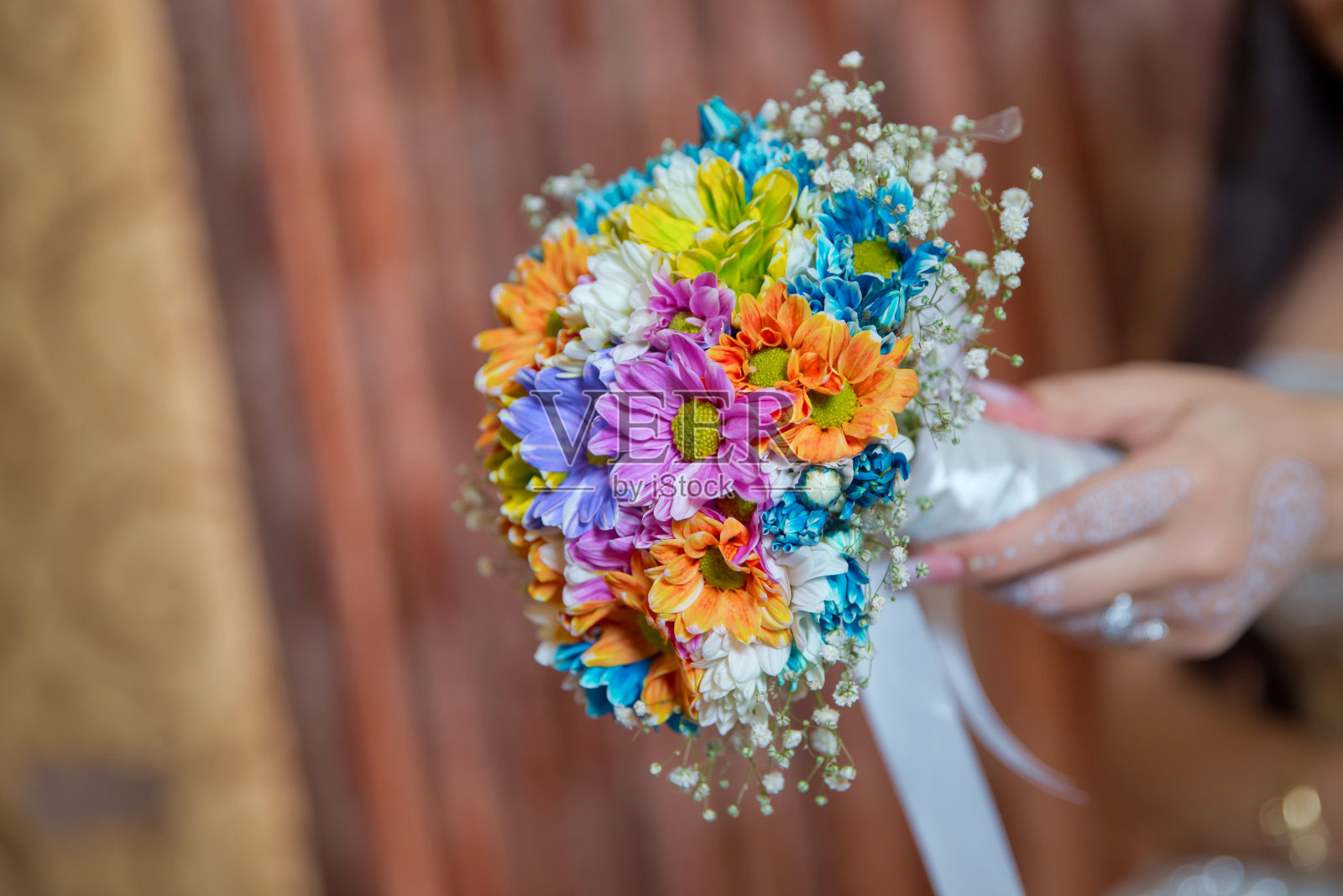他手里拿着一朵结婚花。彩色微距照片详细的花束与色彩丰富的玫瑰,白色的小花和假钻石在玫瑰的中心。照片摄影图片