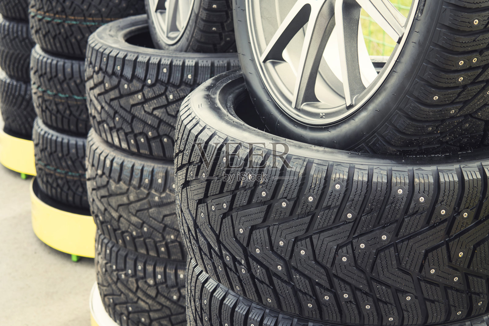 一个有衬里的冬天钉车轮的特写。近距离观察安装在街道上的轮胎螺柱和保护器。冬季轮胎定位户外。一排排暴露的雪地轮胎。轮胎配件照片摄影图片