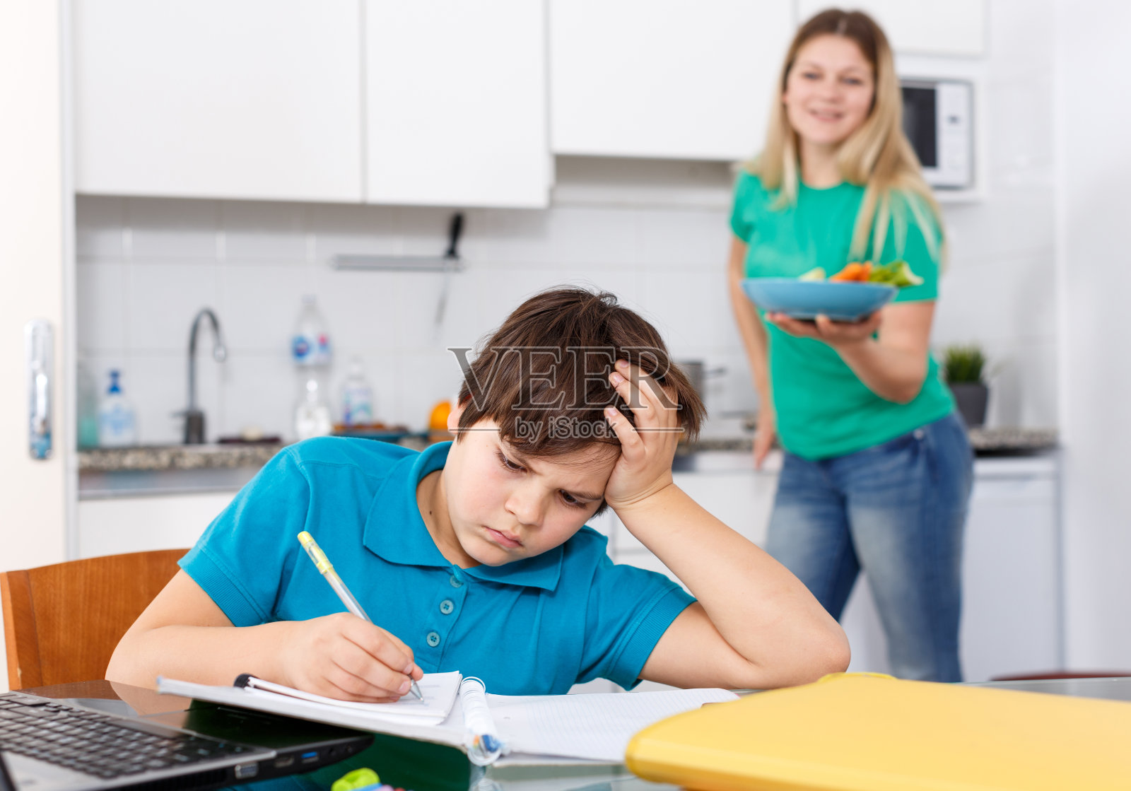 男孩在做作业,妈妈在做饭照片摄影图片