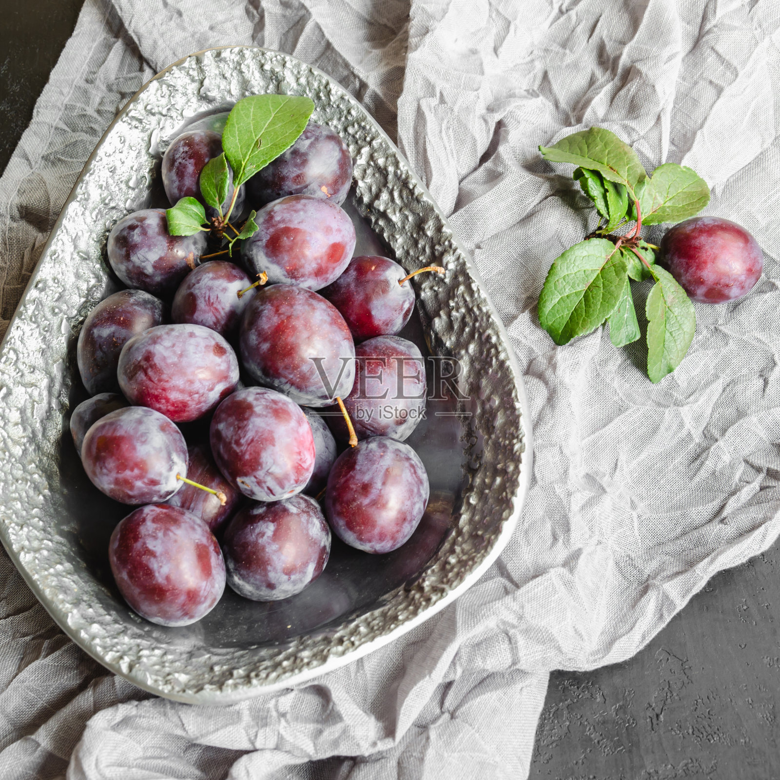 新鲜的有机李子在一个金属复古盘子里。熟透多汁水果的静物照片摄影图片
