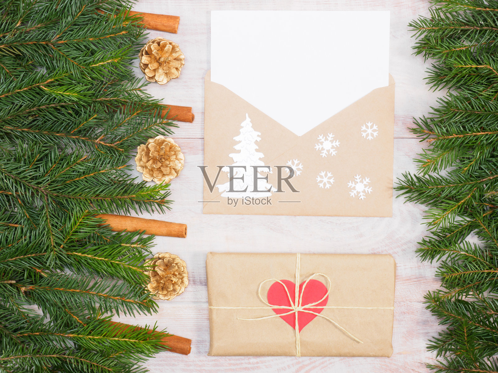 杉树枝与肉桂,球果,雪花,信封,呈现在棕色的木制背景。圣诞节和新年的概念照片摄影图片