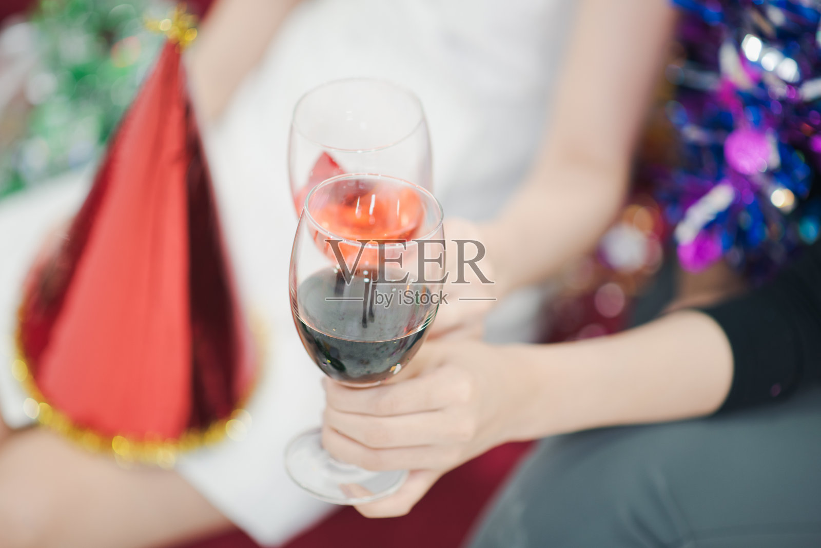 特写一个白人妇女的手,坐在一个红色的沙发上,拿着一杯鸡尾酒酒精。新年聚会概念照片摄影图片