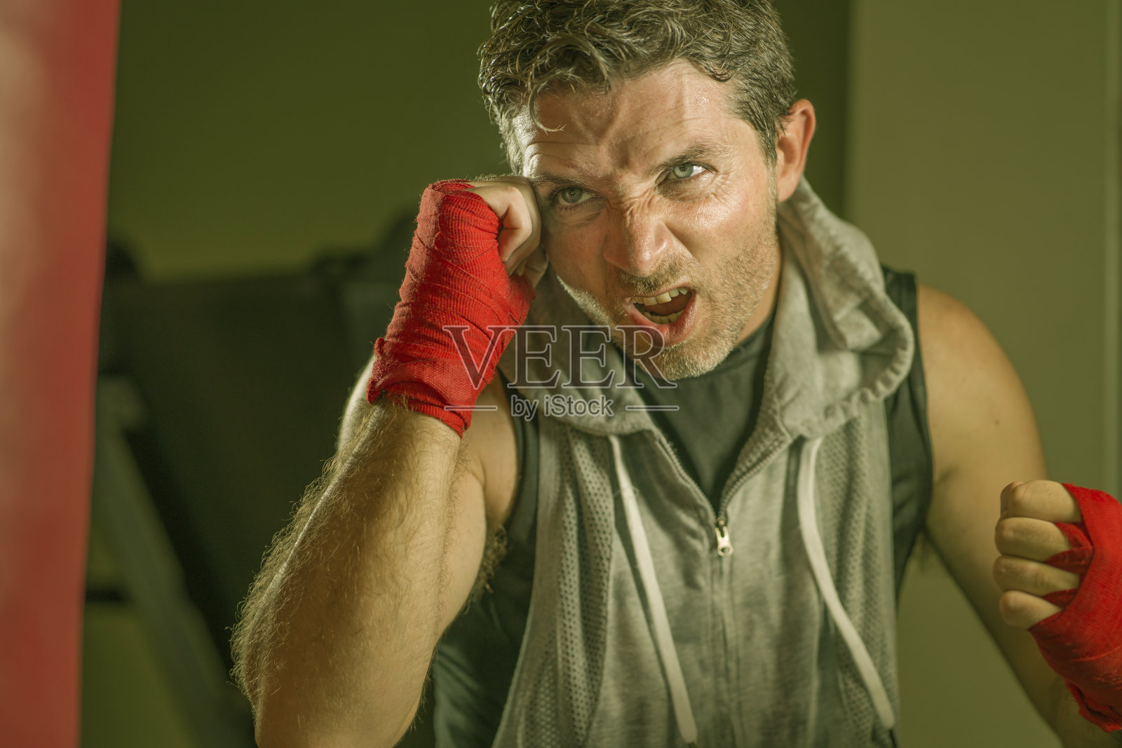 生活方式健身房的肖像年轻有吸引力和凶猛的男子训练拳击在健身俱乐部做沉重的袋拳击锻炼与手和手腕包裹在badass拳击手的样子照片摄影图片