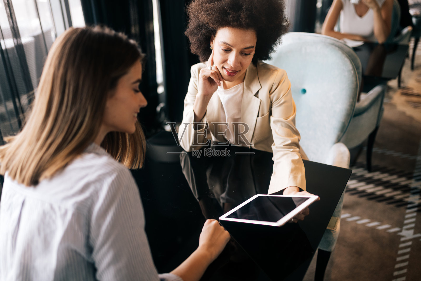 快乐的笑着的女孩在咖啡馆喝咖啡和讨论新的创意项目照片摄影图片