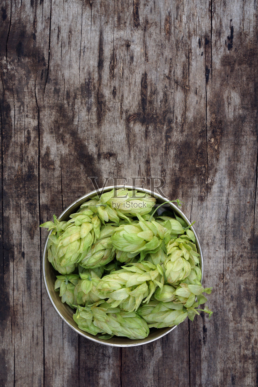 啤酒花细枝框架在木制破裂的桌子背景和铜碗。啤酒原料。照片摄影图片