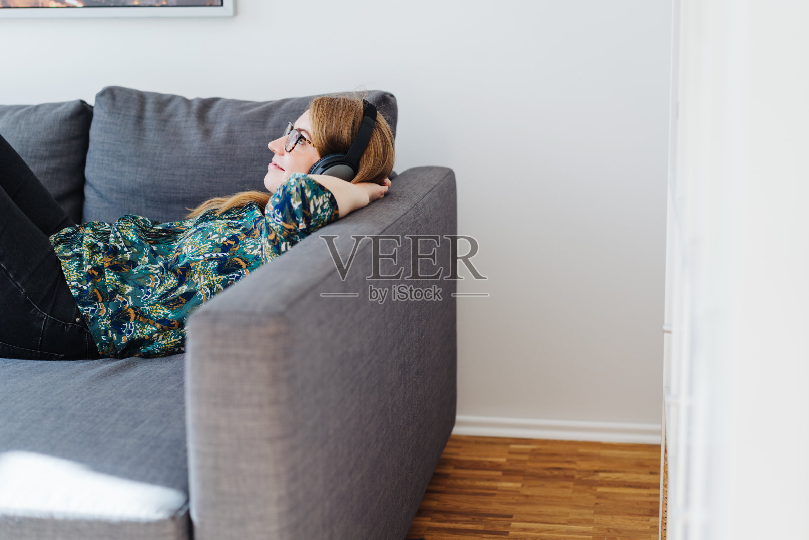 一个年轻女子坐在沙发上听着音乐照片摄影图片