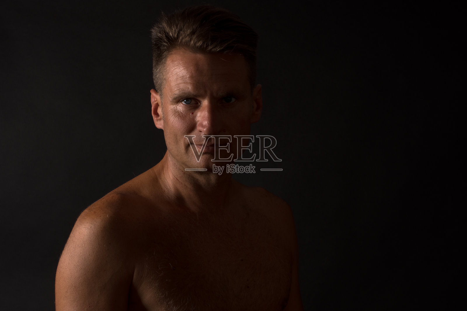 成熟男人的肖像与赤裸的躯干在分裂的光照片摄影图片