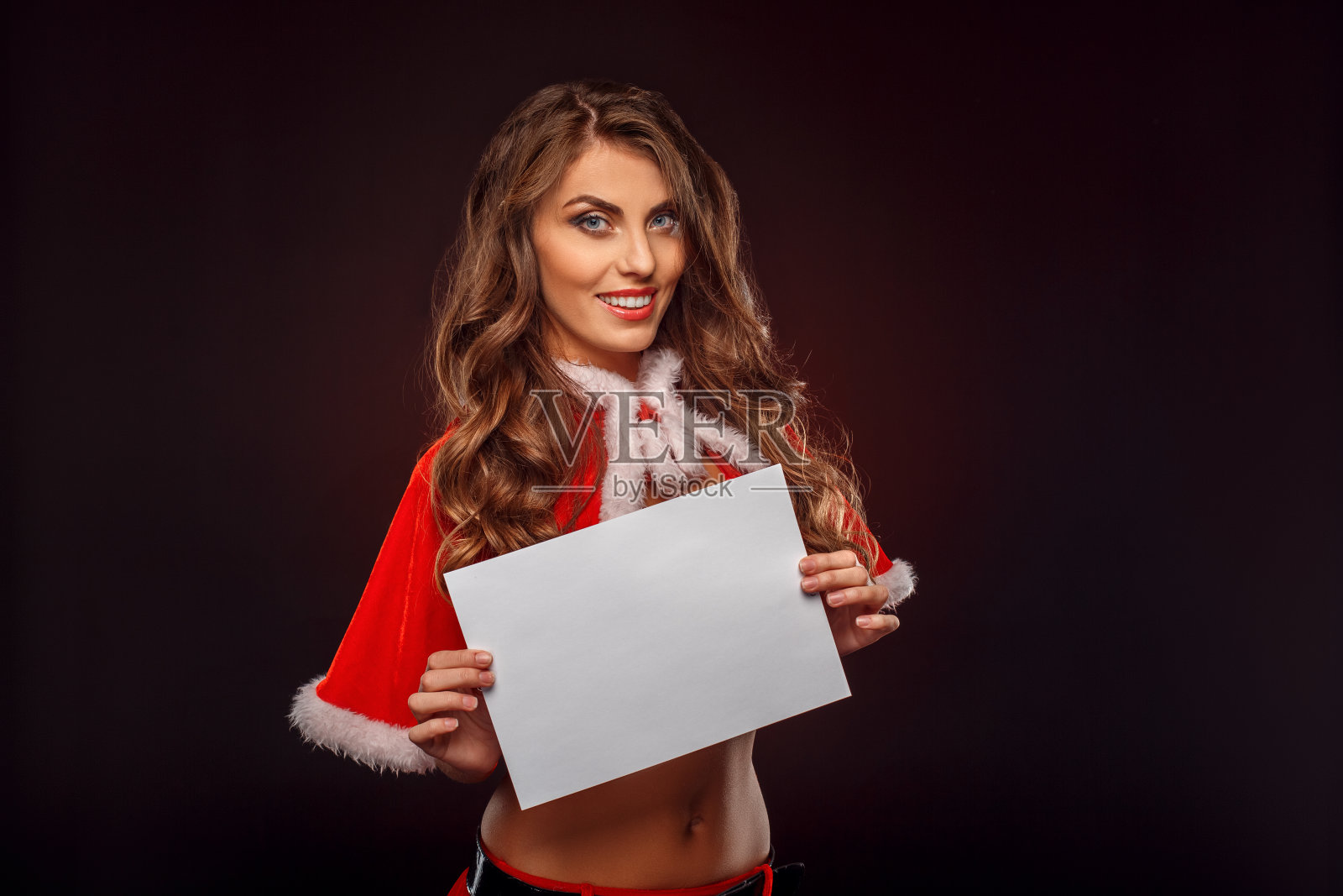 圣诞和新年。女人在圣诞老人服装孤立站在黑色与纸微笑好玩的特写照片摄影图片