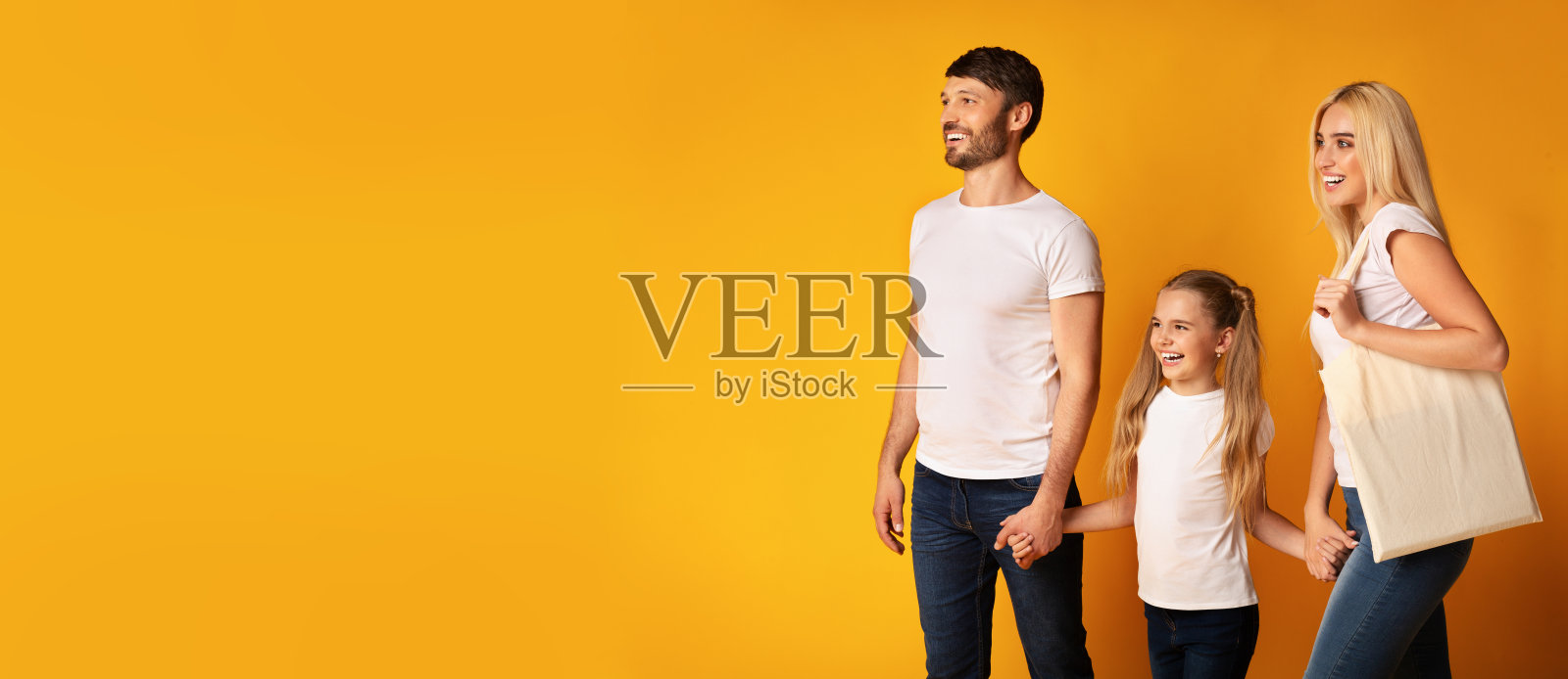 幸福的家庭牵着手走过黄色的背景,全景照片摄影图片