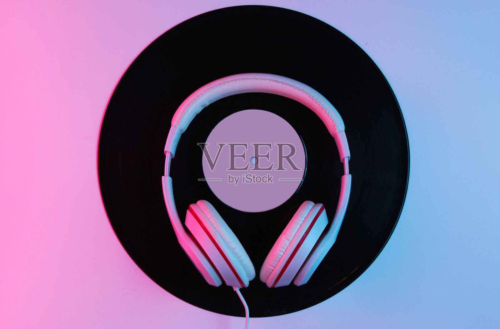 复古风格的音乐概念。经典耳机,黑胶唱片与梯度粉蓝色霓虹灯。流行文化。80年代前视图照片摄影图片