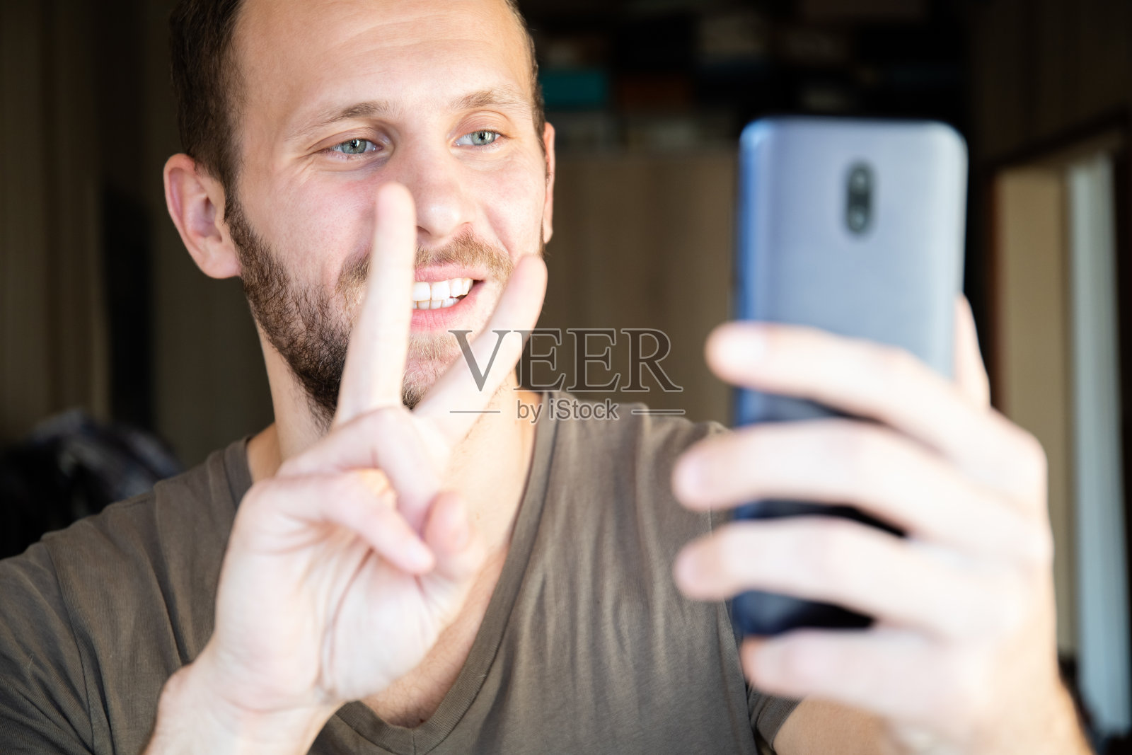 一个带着微笑在家里通过耳机通过视频连接的智能手机聊天的人照片摄影图片