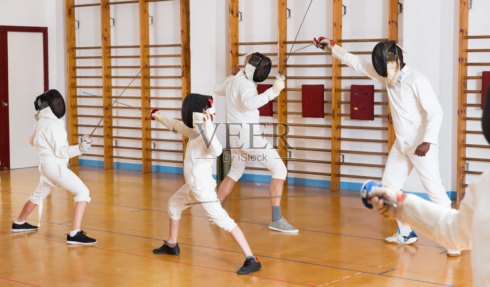 成人和青少年穿着击剑制服与花剑练习照片摄影图片