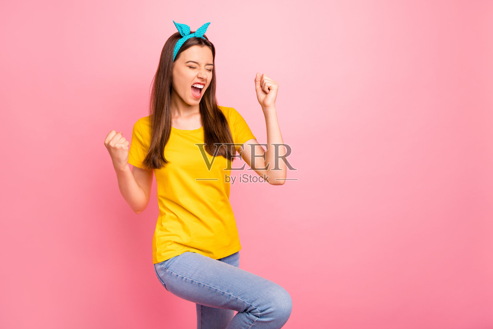 欢快的青年高举拳头,高喊耶,穿着黄色t恤孤立在粉红色的背景照片摄影图片