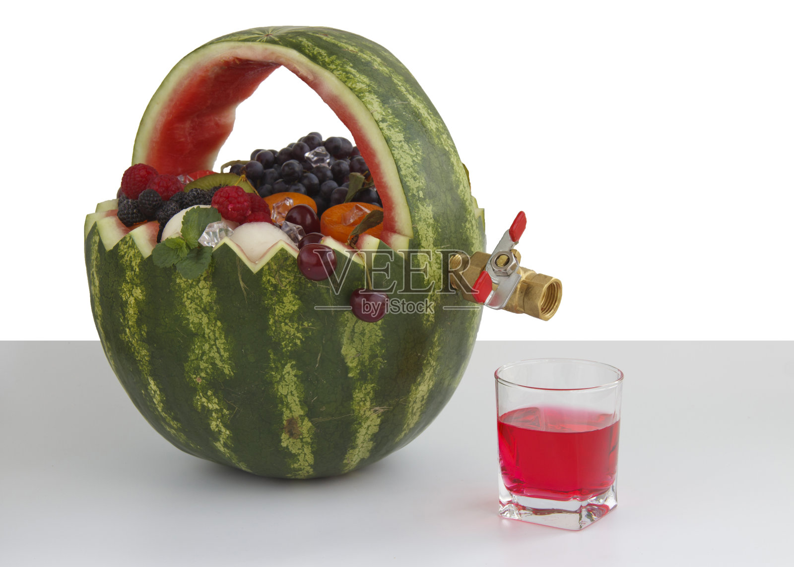 水果篮和果汁排水龙头。这个篮子是用西瓜做的,里面装满了不同的水果照片摄影图片