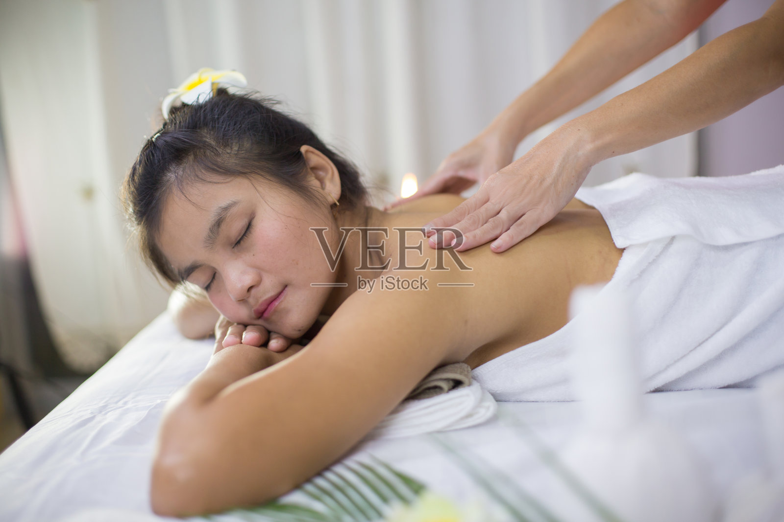 一位亚洲妇女正在按摩一个草药水疗中心,有一种放松,快乐的感觉。照片摄影图片