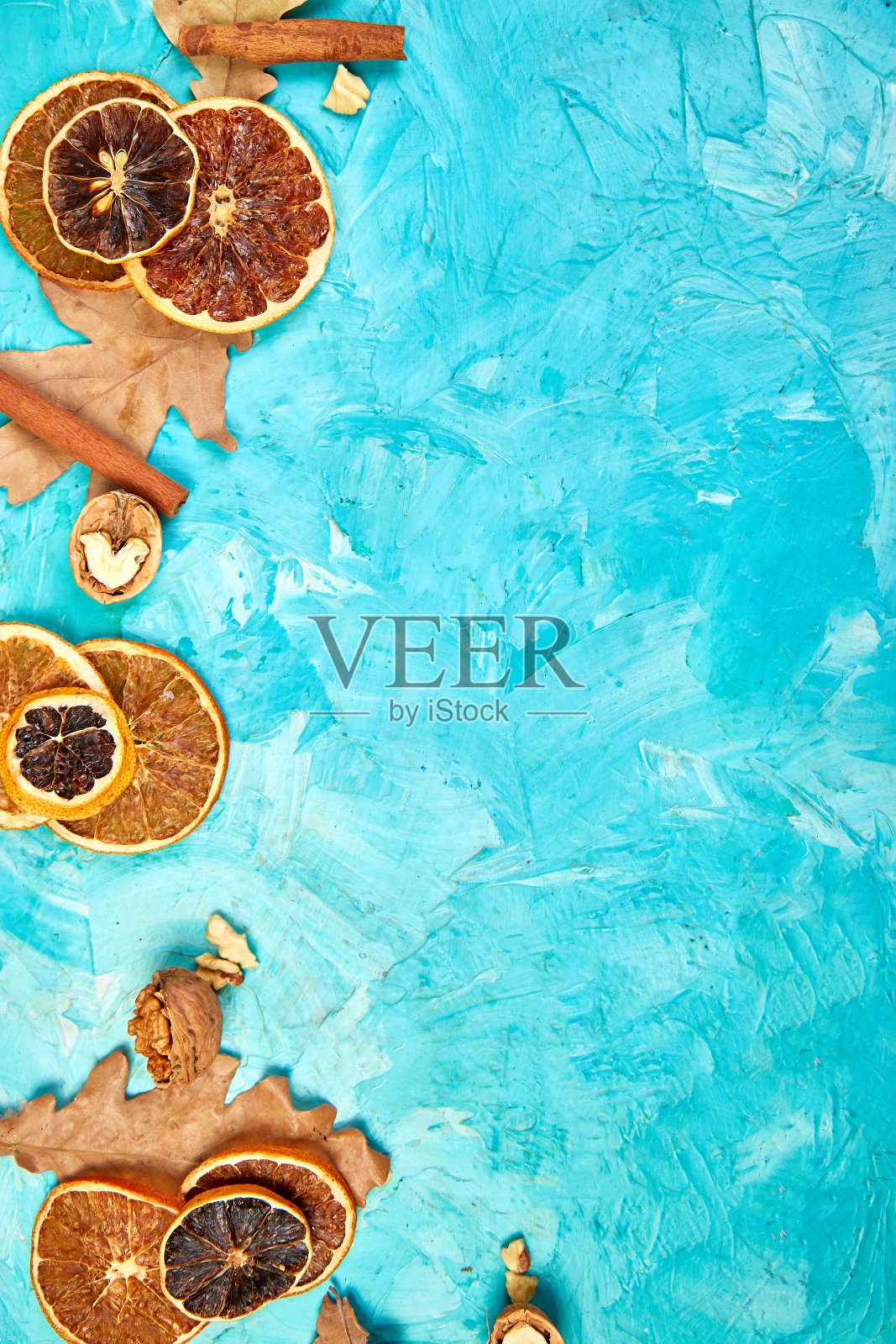 秋天的组成背景与干橘子片,树叶和肉桂在蓝色的背景,秋天的概念,平躺,俯视图照片摄影图片