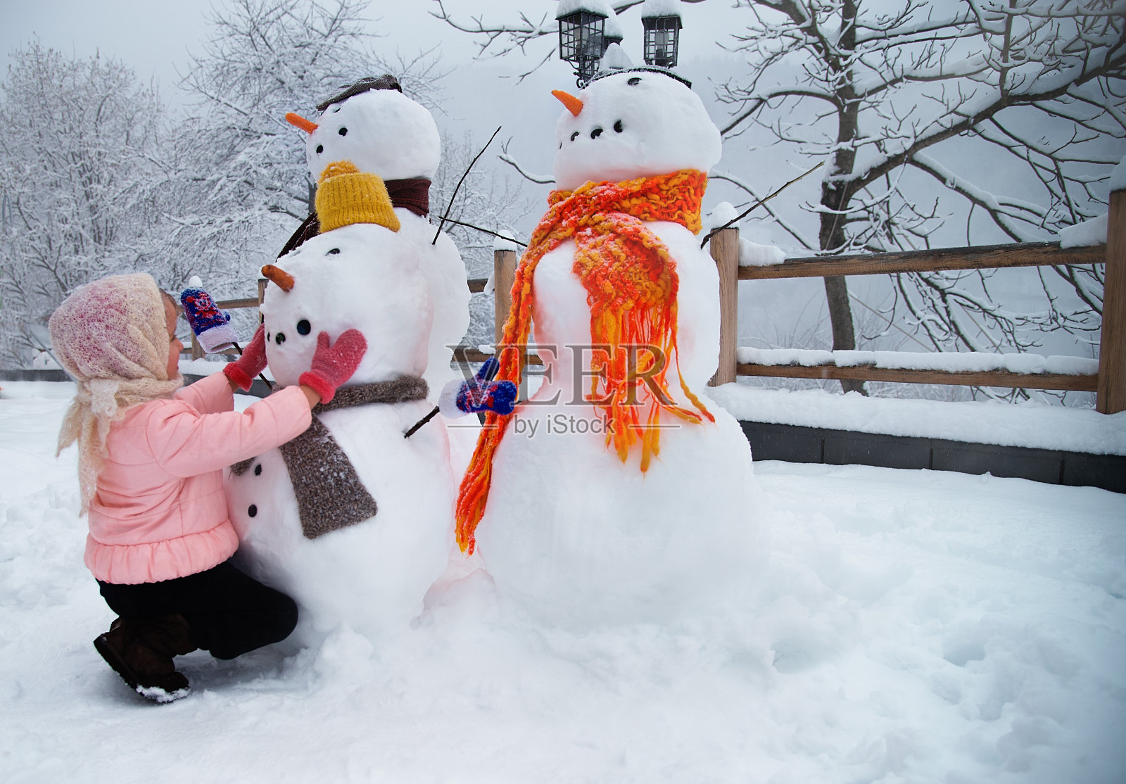 堆雪人的小女孩照片摄影图片