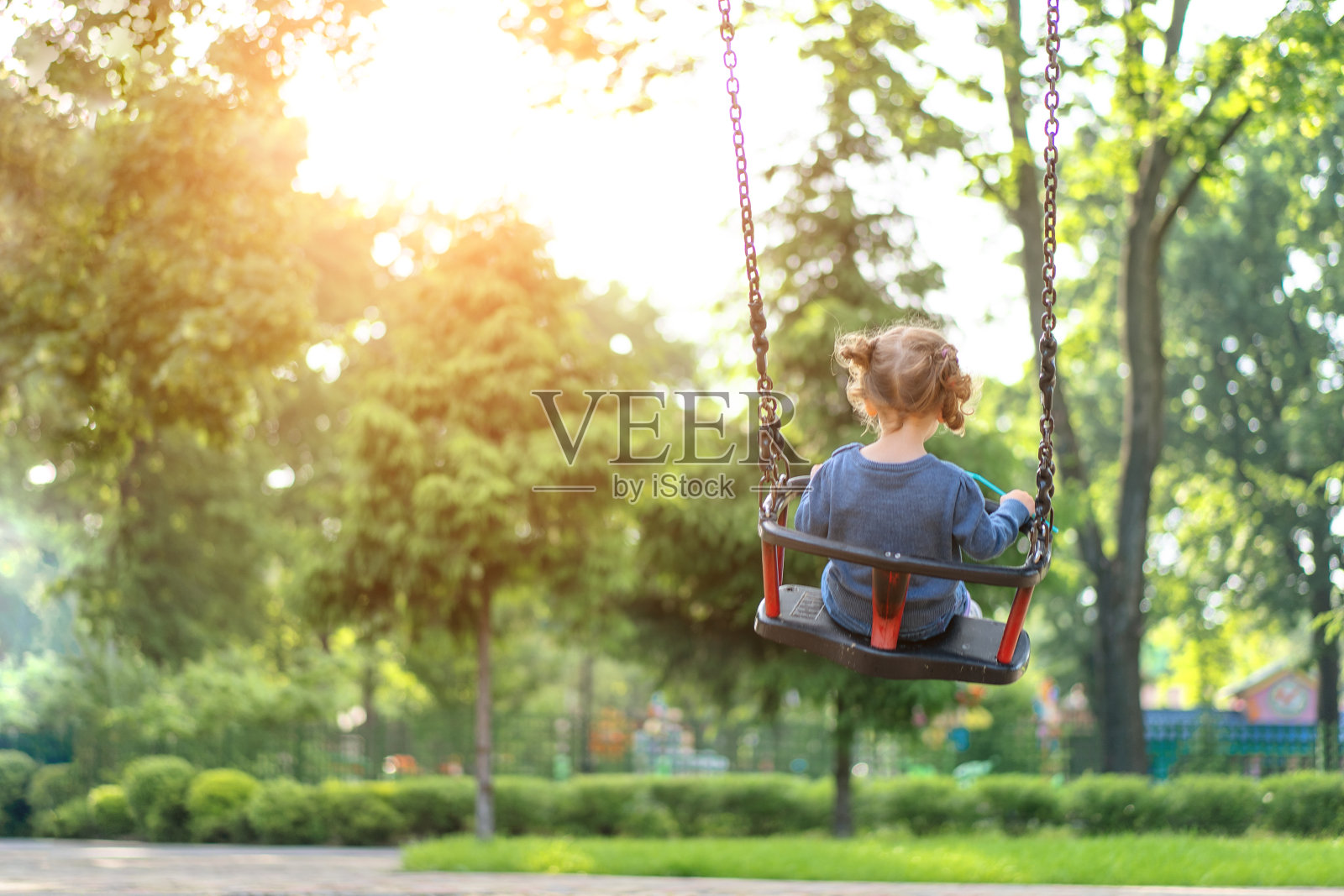 无法辨认的小高加索女孩在操场上骑秋千阳光明媚的夏日后视图照片摄影图片