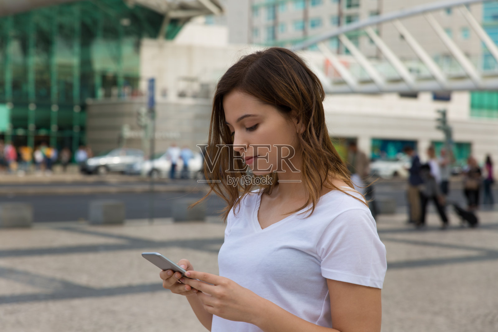 漂亮的年轻女子在街上用智能手机照片摄影图片