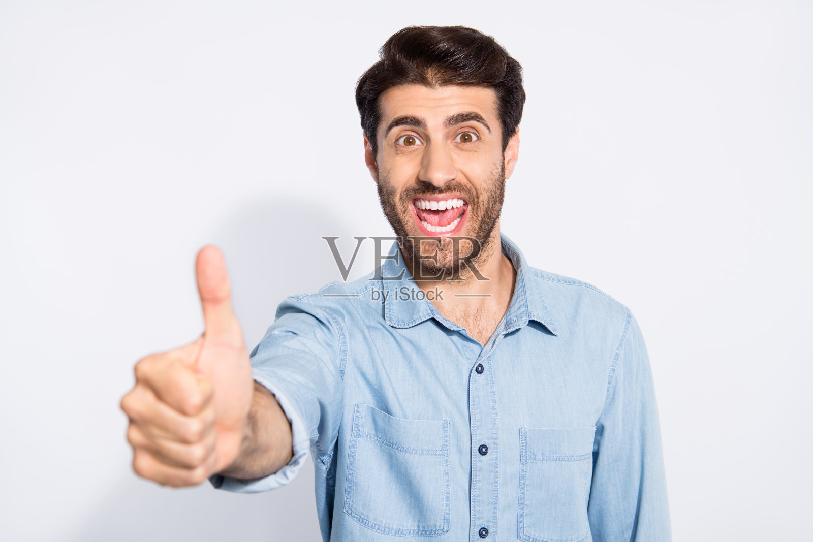 近距离的照片惊人的混合种族多民族男子举起大拇指表达积极的态度穿休闲牛仔衬衫孤立的白色背景照片摄影图片