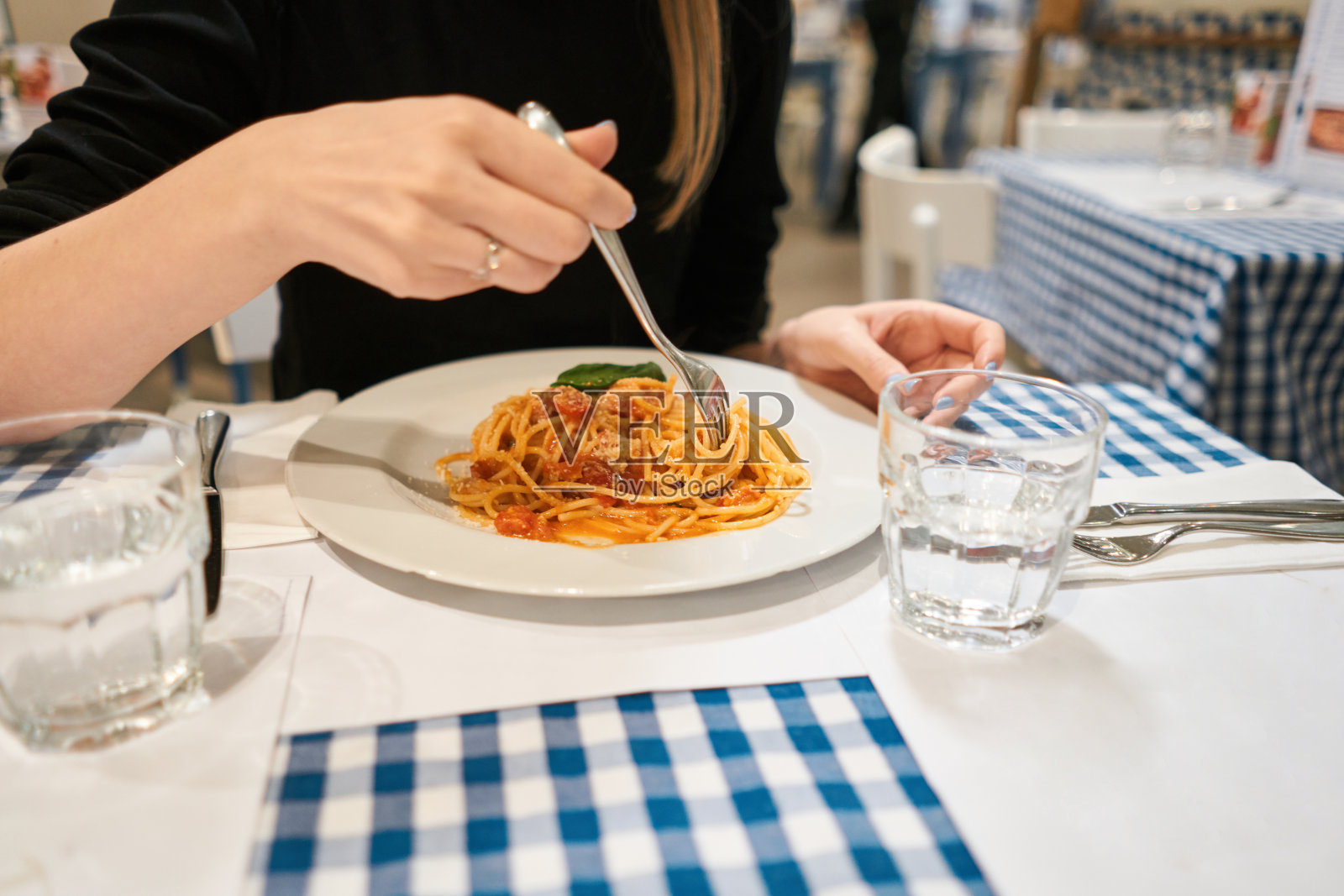 特写的意大利肉酱面用叉子卷起来。帕玛森芝士。年轻女子吃意大利面加西红柿和肉。照片摄影图片