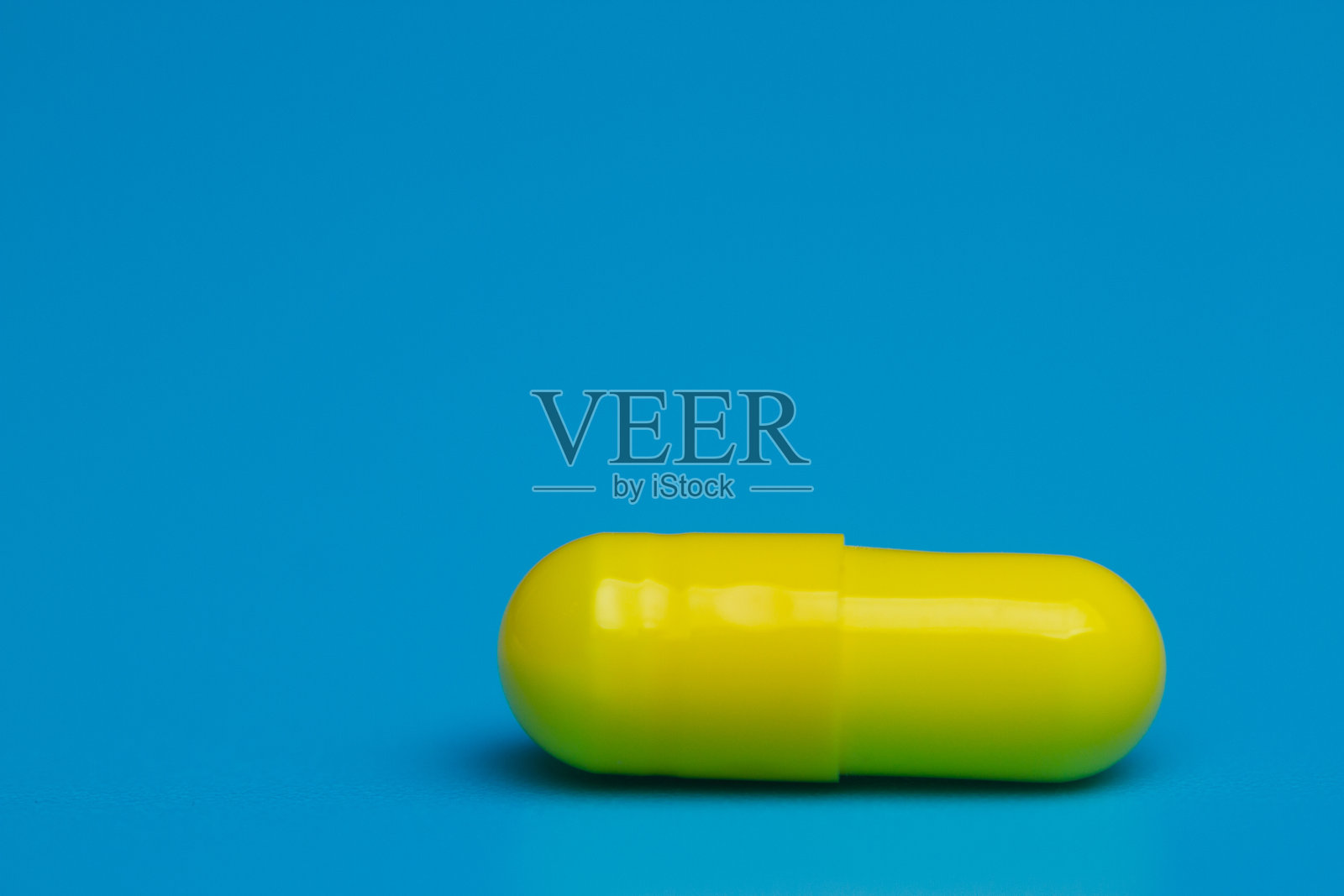 蓝色背景上的黄色药丸照片摄影图片