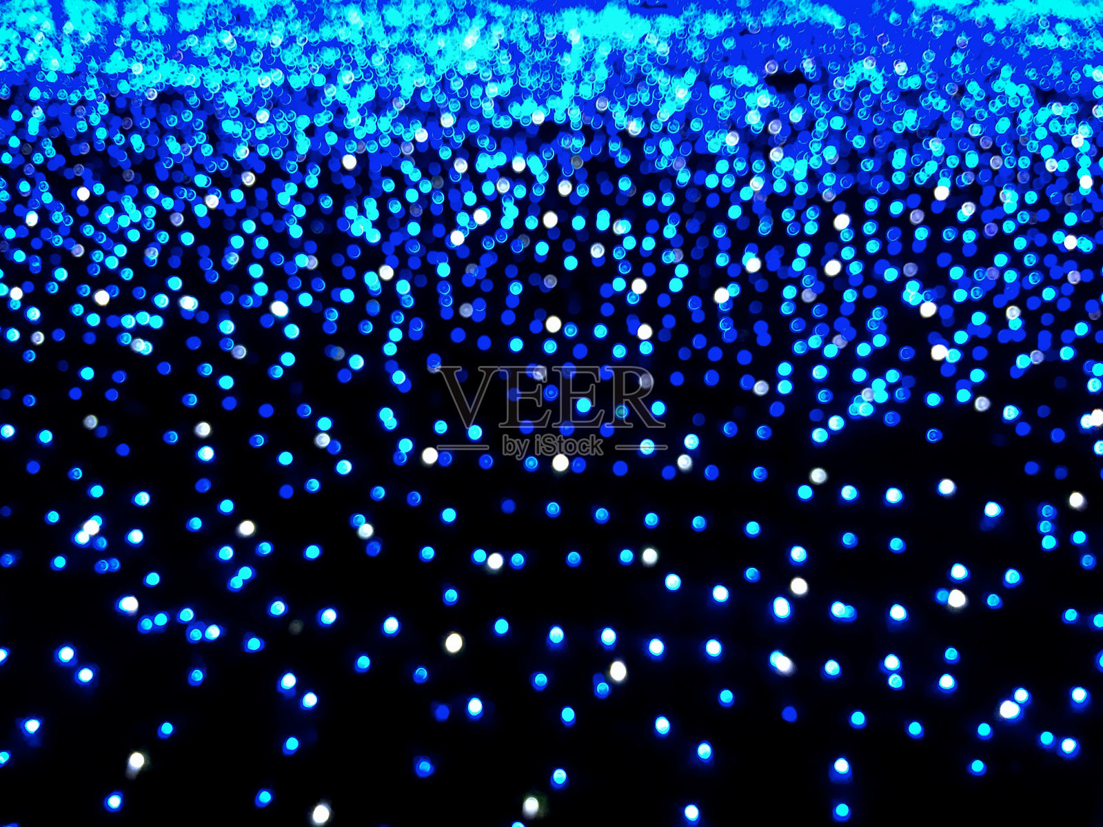 在黑暗中散焦的蓝色灯光的背景。散景效果照片摄影图片