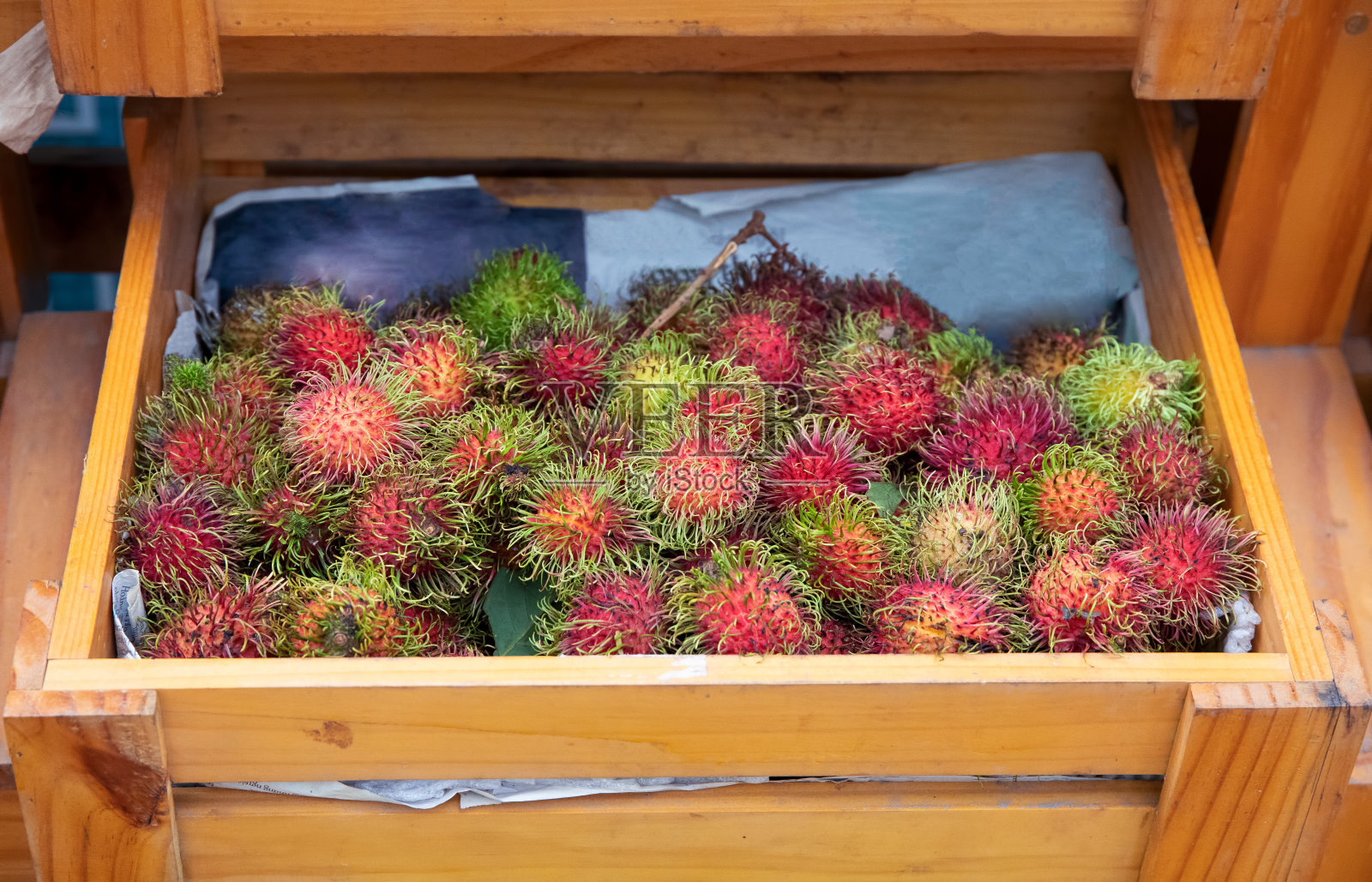 热带水果红毛丹木箱。亚洲乡村有机市场上的外来水果。亚洲的水果季节。照片摄影图片