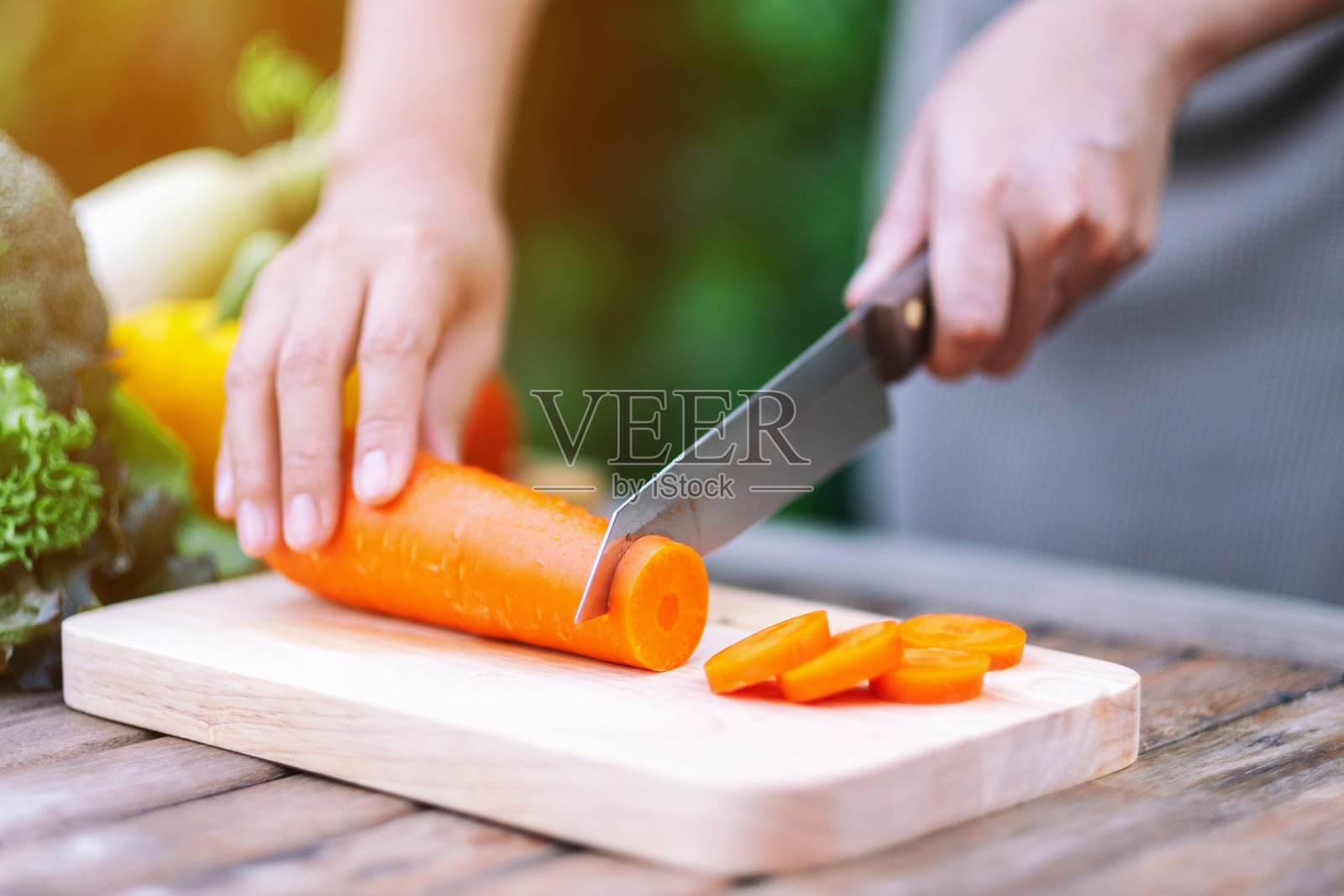 用刀在木板上切胡萝卜的手照片摄影图片