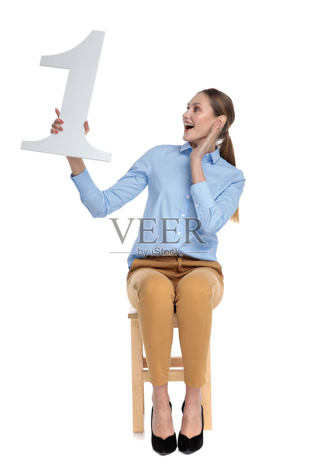 骄傲的年轻女子,穿着蓝色衬衫,举着一号牌子照片摄影图片