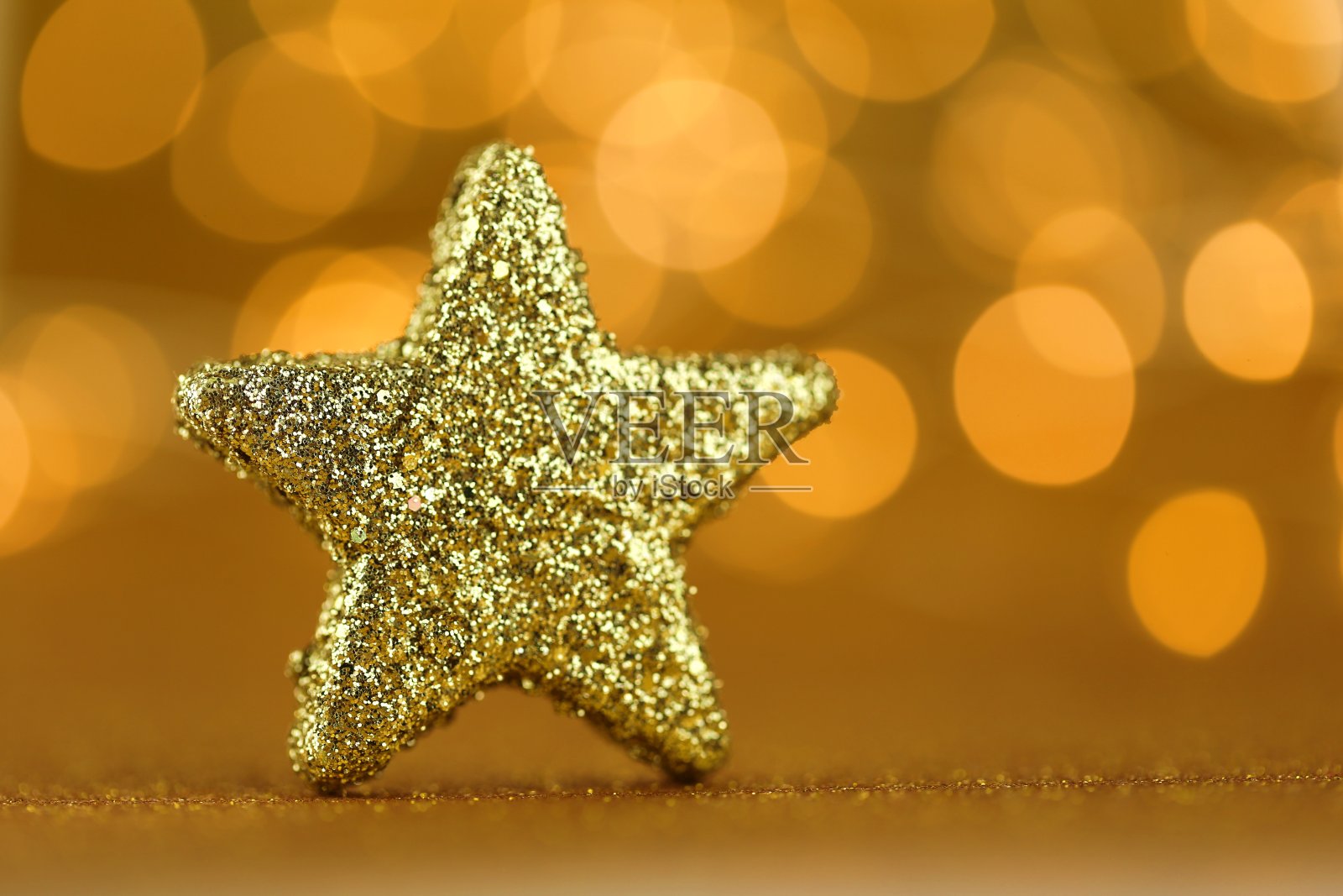 圣诞节日的背景。金色闪光星在金色闪亮的背景与黄色闪光散焦。圣诞节和新年的背景。假期壁纸。金色闪亮的壁纸。照片摄影图片