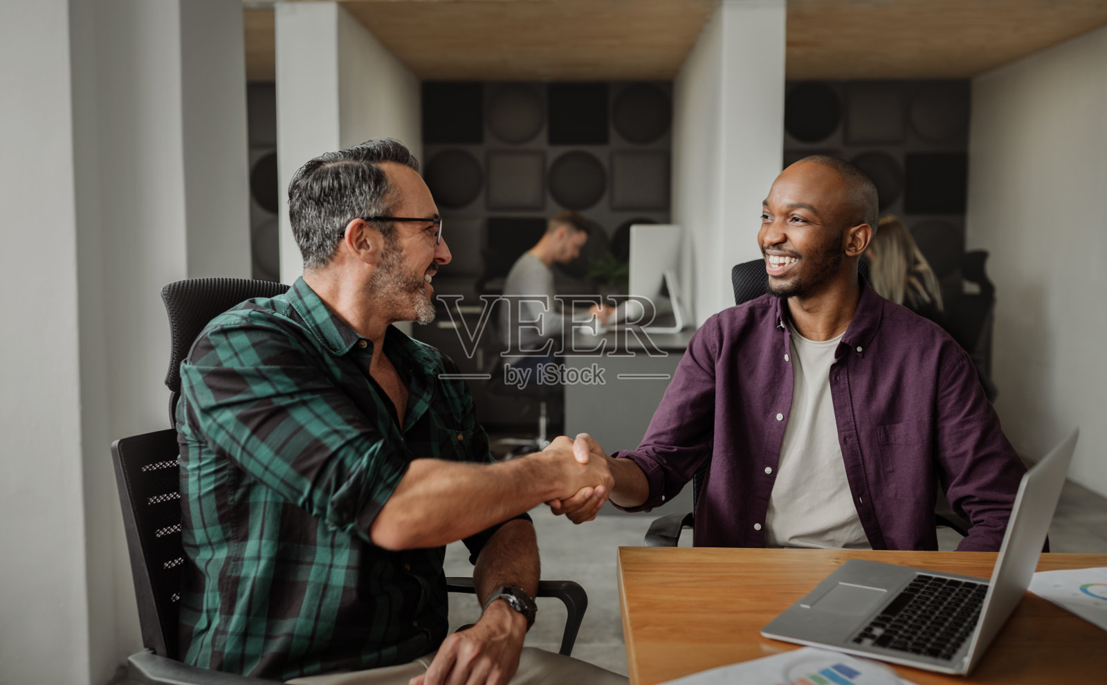 企业家们在现代的共同工作空间里握手,人们在后台工作照片摄影图片