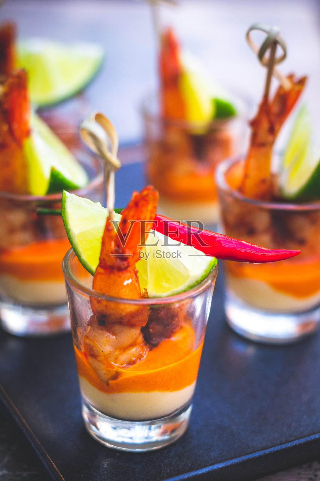 鲜虾串在克里奥尔酱和奶油芝士酱和青柠角在小酒杯照片摄影图片