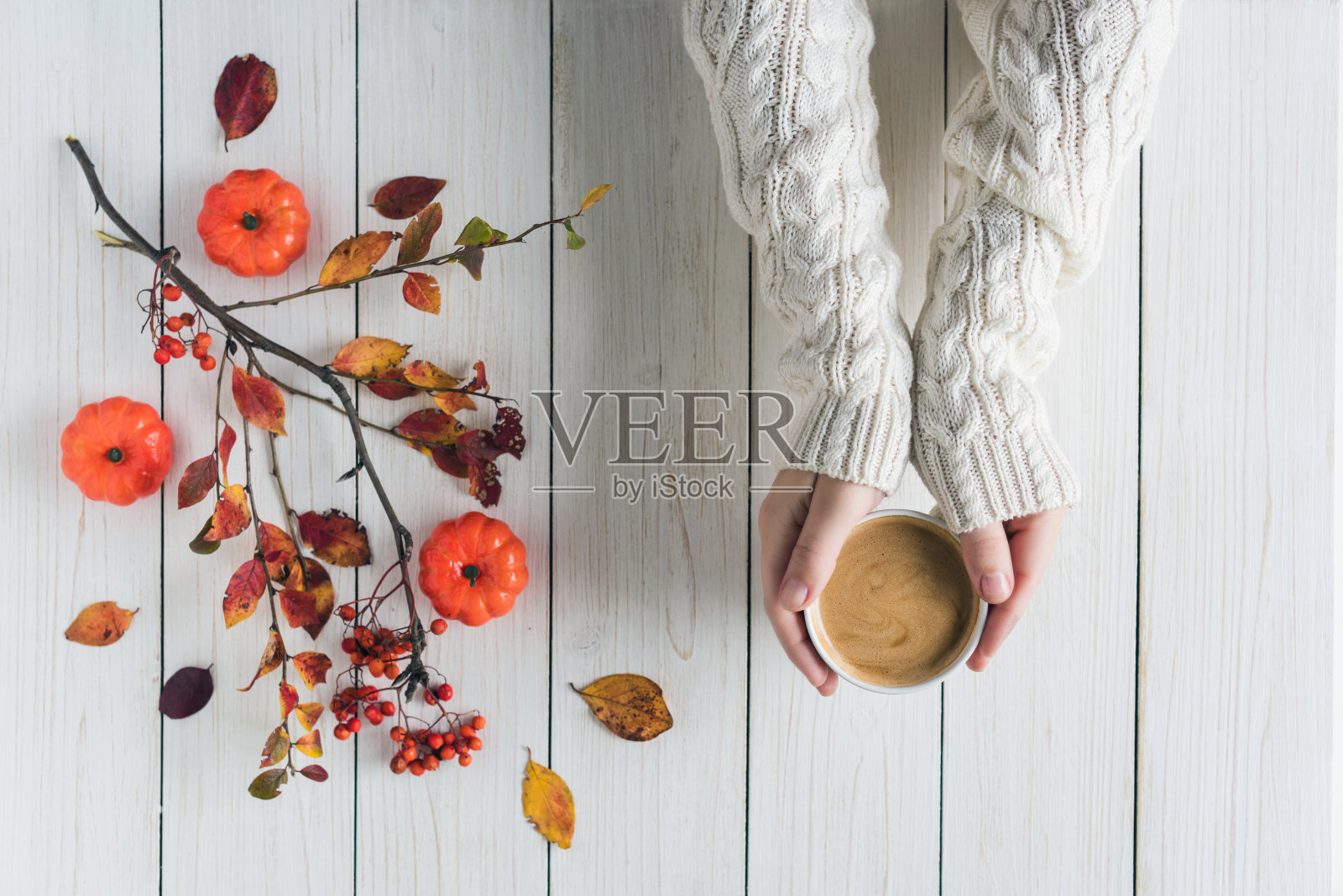 拿着一杯咖啡、树叶、小南瓜和白色复古木板上的花楸的女人。背景。秋天,秋天的概念。平躺,俯视图。照片摄影图片
