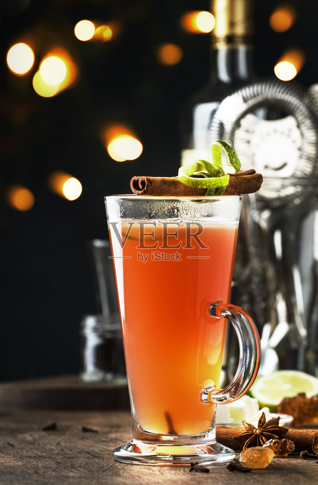 热黄油朗姆酒,秋季或冬季酒精鸡尾酒,与苹果和柠檬汁,黑色朗姆酒,蜂蜜,肉桂在高脚杯在黑暗的背景和雨滴照片摄影图片