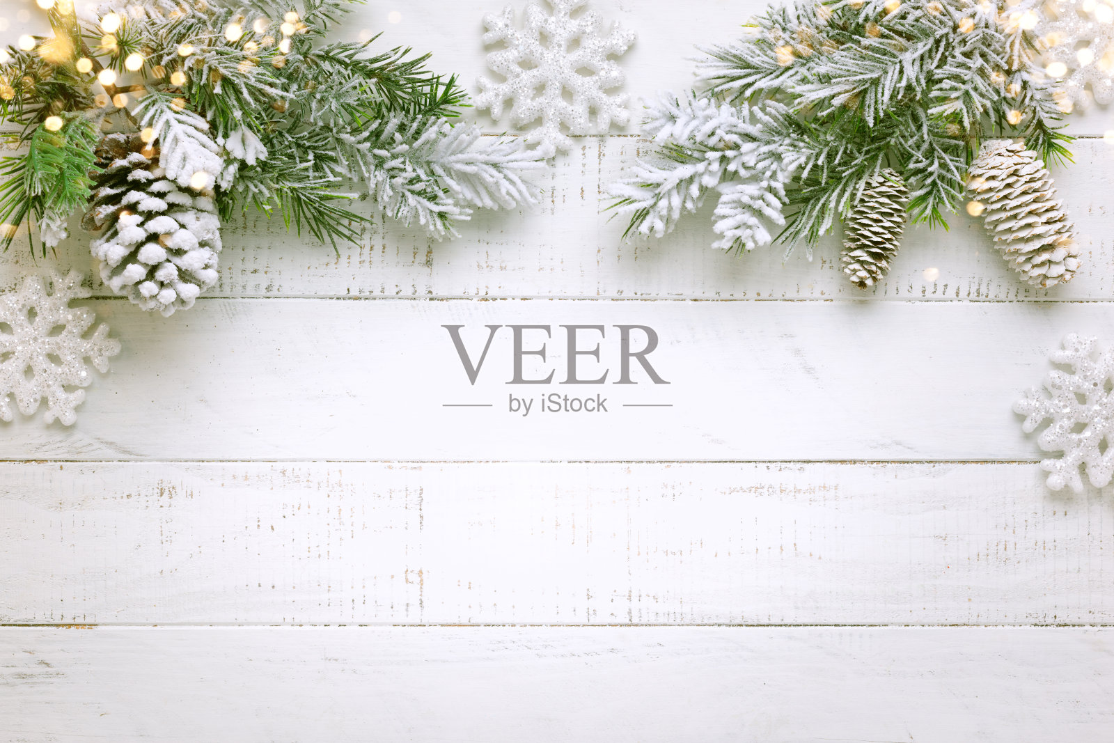 白色的木质背景上,白雪覆盖着圣诞树的树枝和松果照片摄影图片