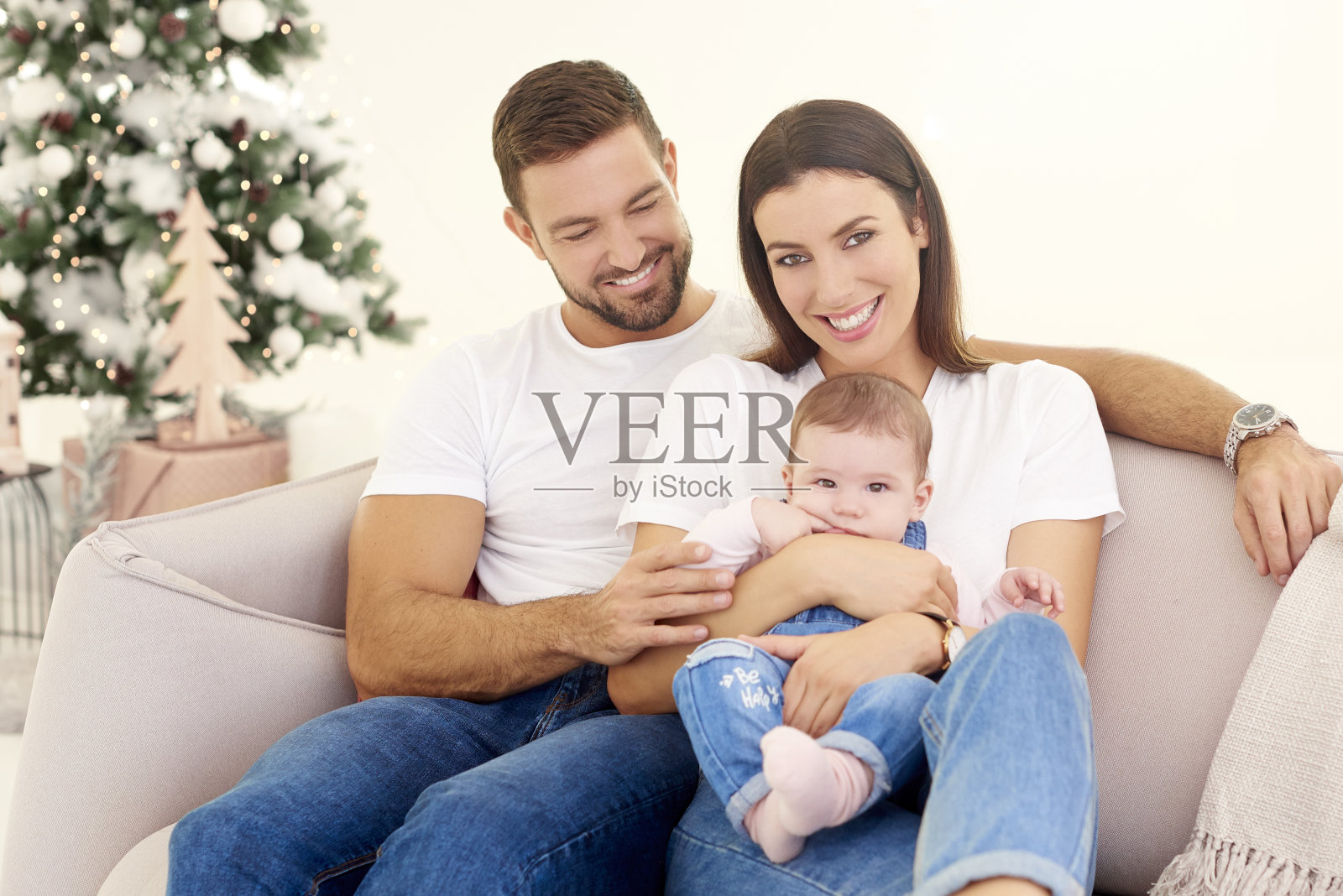 可爱的家庭和他们的宝贝女儿在家里的沙发上休息照片摄影图片