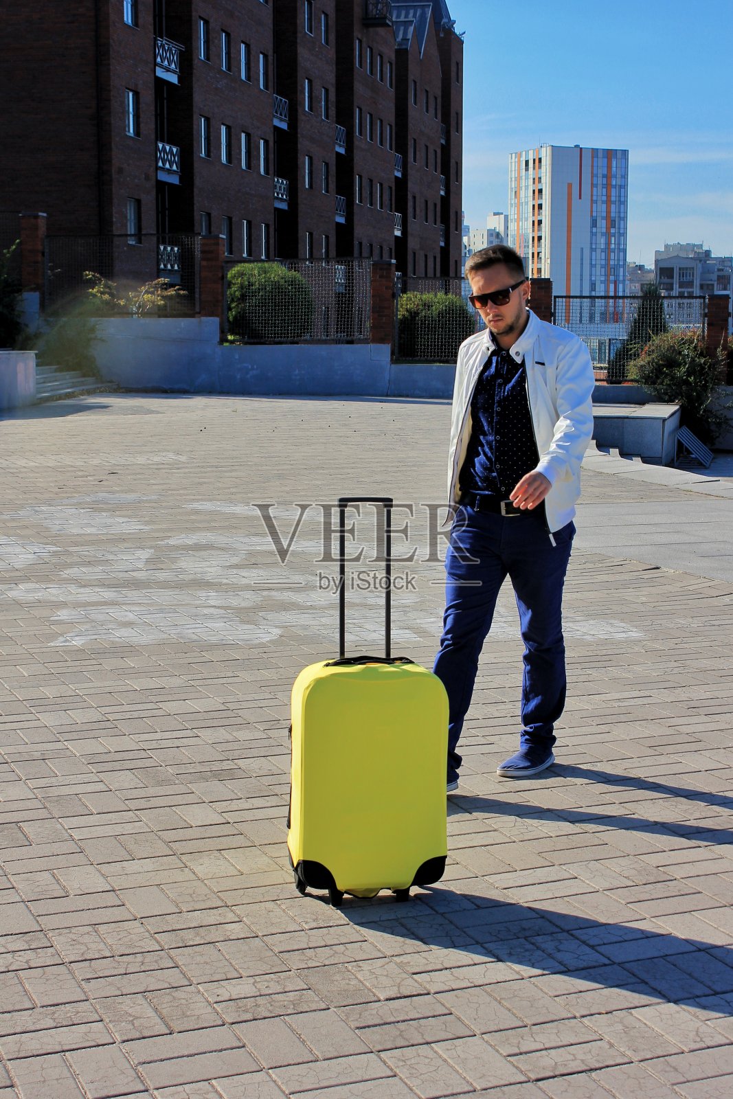 独自旅行的男人,带着黄色的行李和城市背景照片摄影图片