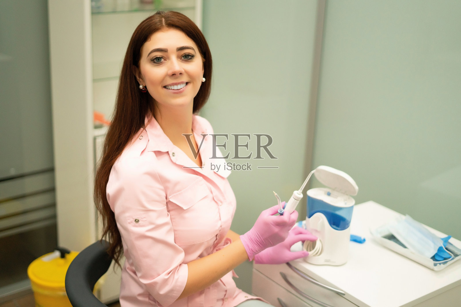 美丽的女牙医显示冲洗工作。牙医演示卫生设备。牙科,现代工具。照片摄影图片