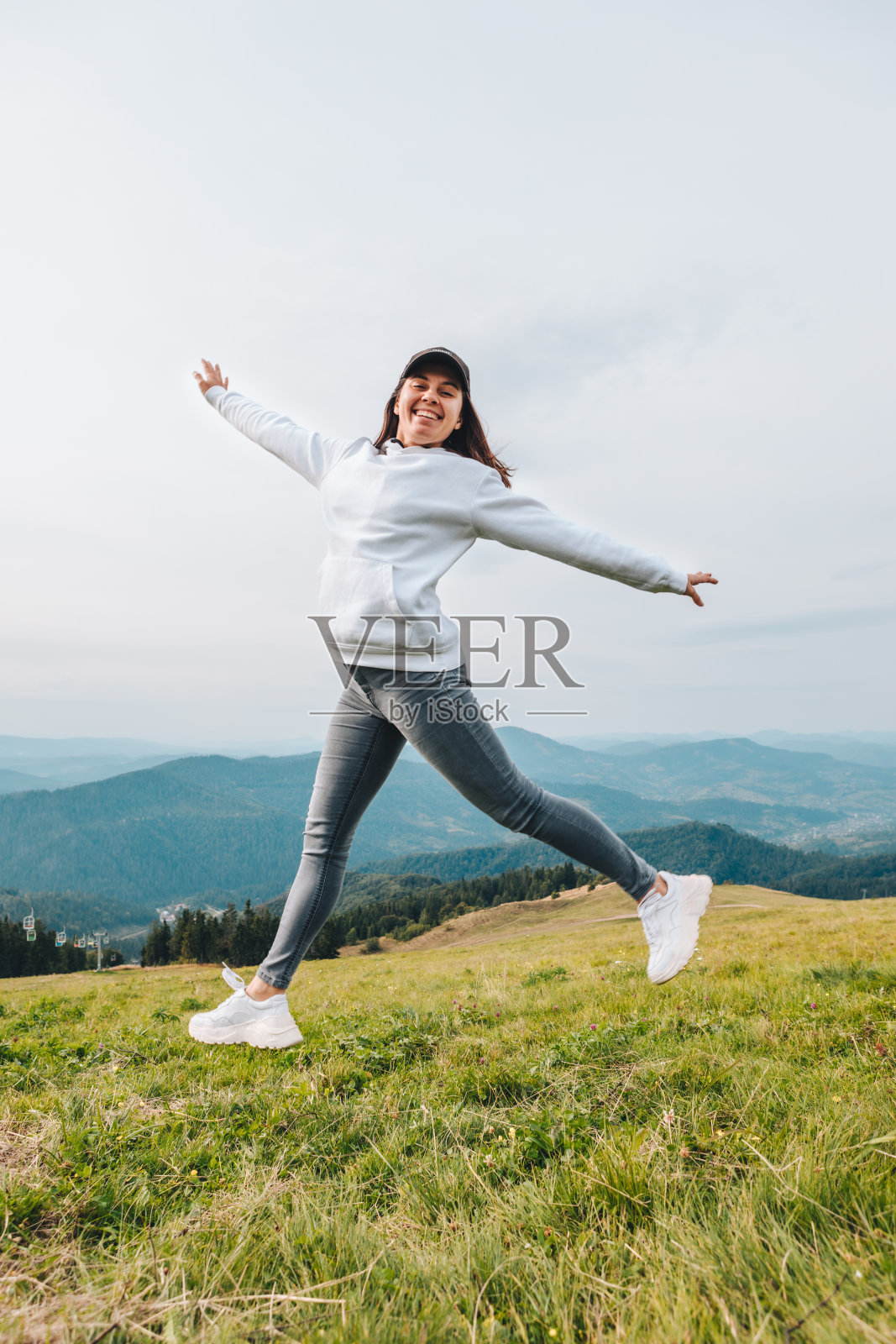 女子在山顶上跳跃,美丽的山谷景色在背景中徒步概念照片摄影图片