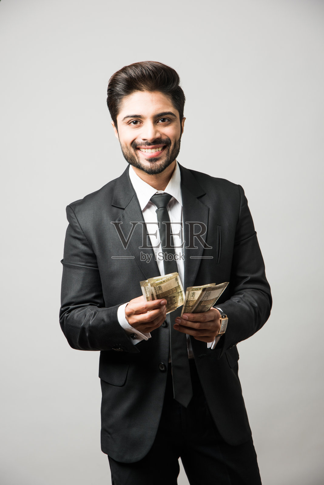 快乐的留着胡子的印度商人手里拿着扇子,500卢比纸币,孤立地站在白色背景下照片摄影图片