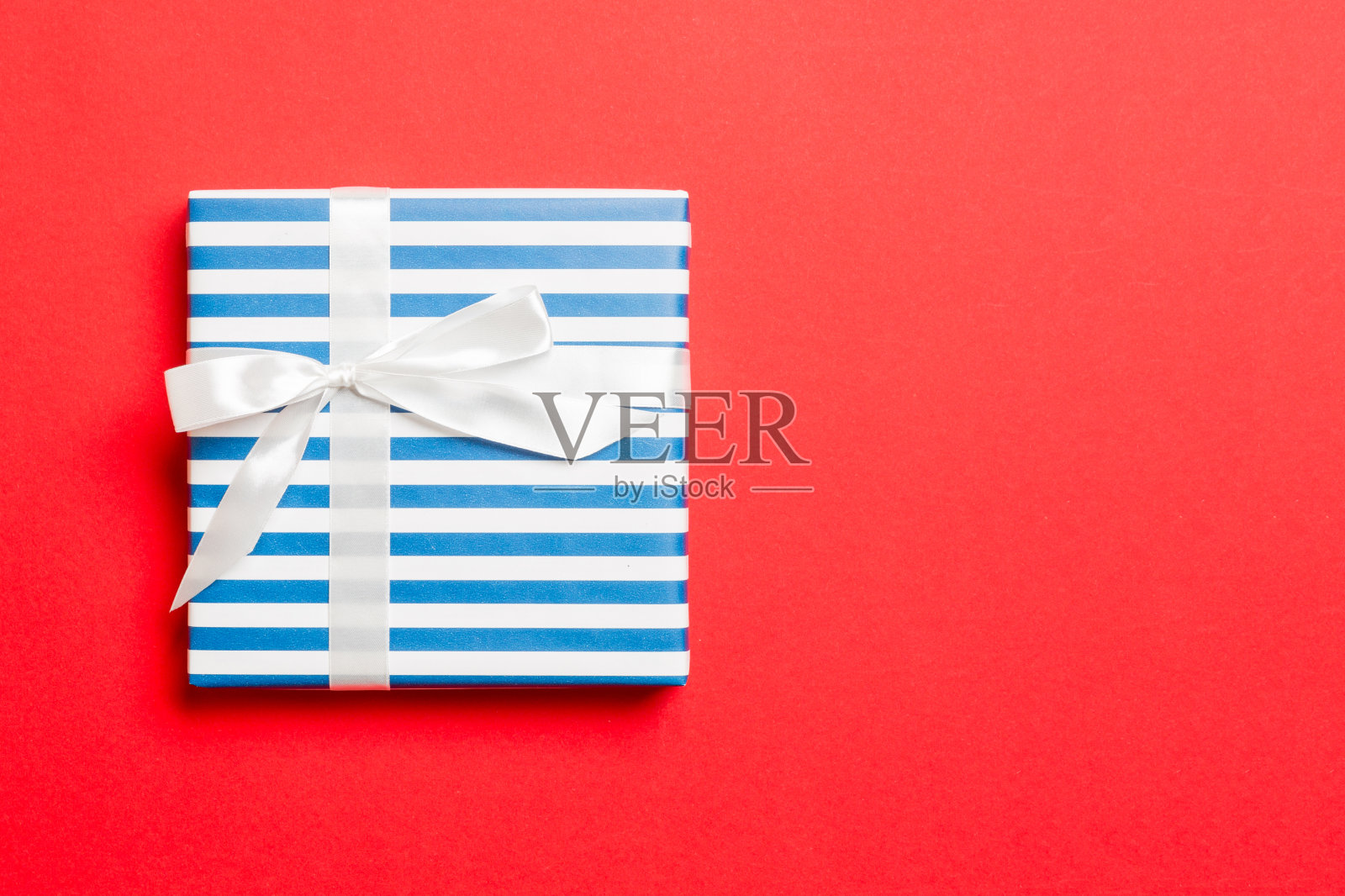 礼品盒与白色蝴蝶结在手圣诞节或新年的红色背景,俯视图与拷贝空间照片摄影图片