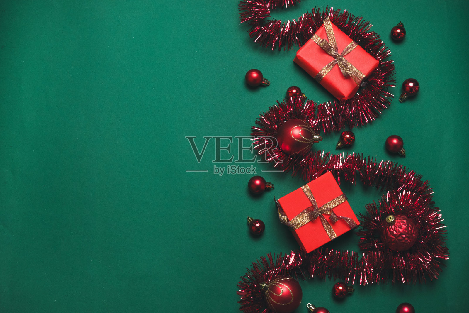 迷你圣诞概念背景与红色礼盒与金色丝带和红色球在绿色背景。平铺式构图,俯视图。照片摄影图片